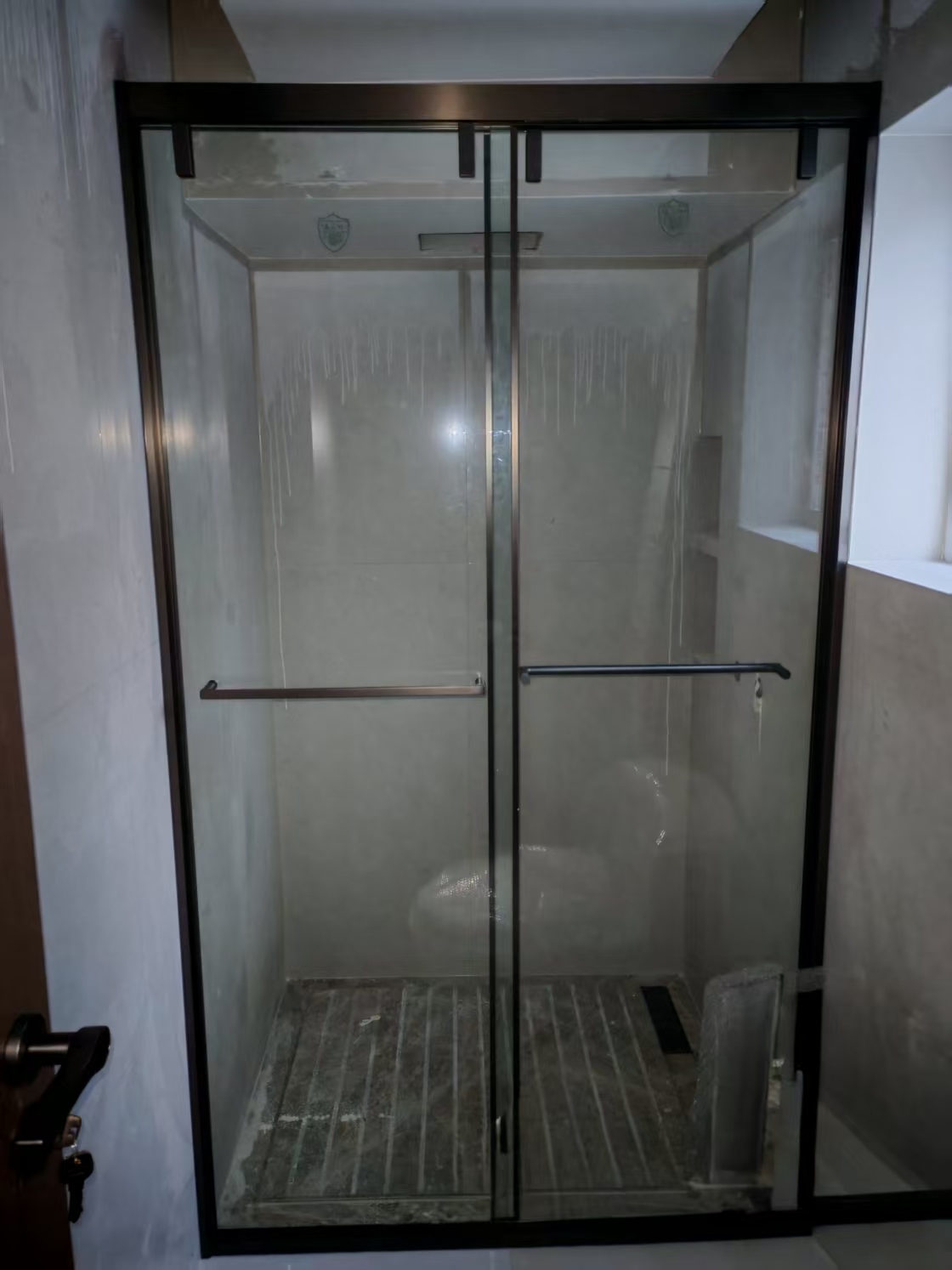 Coastal Estate — frameless dark-glass shower enclosure with brushed hardware